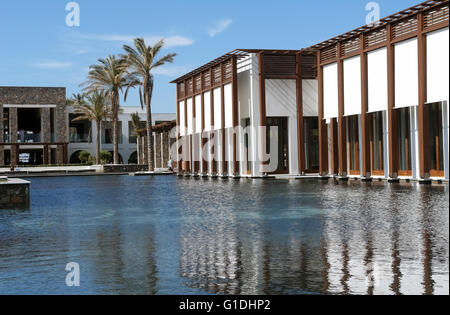 HERAKLION, CRETE, GREECE - MAY 13, 2014: Big blue swimming-pool, modern building with columns, palms in luxury class hotel Stock Photo