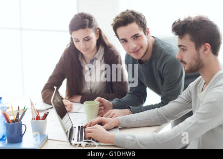 Group of college students at desk using a laptop, networking and studying together, education and learning concept Stock Photo