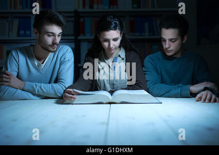 Young college students reading a book together late at night, knowledge and learning concept Stock Photo