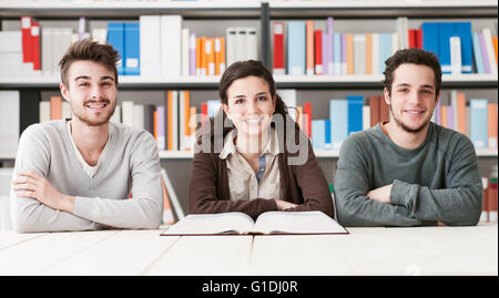 Young college students at the library studying together, they are reading a book, knowledge is power concept Stock Photo