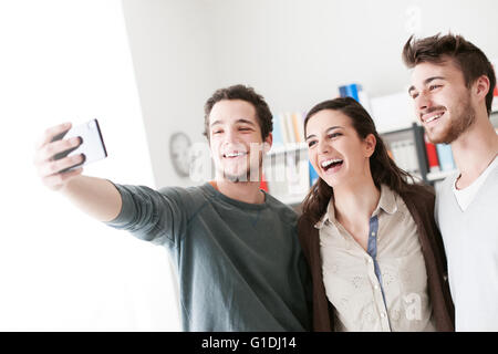 Smiling happy teenagers taking selfies with a mobile phone, sharing, technology and friendship concept Stock Photo