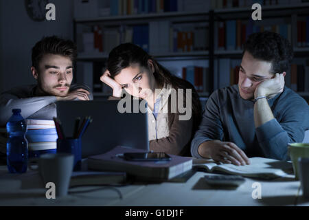 Tired students studying late at night, they are staring at the laptop screen and falling asleep Stock Photo