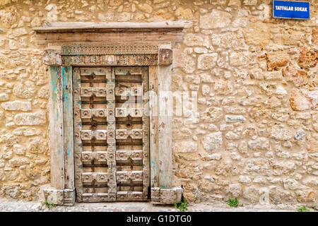 NORTH CYPRUS KYRENIA OLD TOWN CARVED WOODEN DOOR AND OLD STONE WALL WITH STREET SIGN TAYFALAR SOKAK Stock Photo