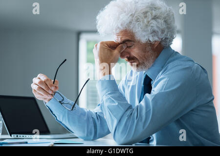 Stressed exhausted businessman sitting at office desk, failure and loss concept Stock Photo