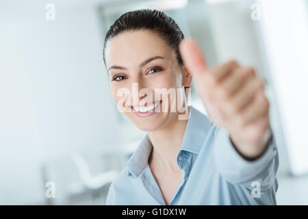 Beautiful businesswoman thumbs up smiling at camera, success and achievement concept Stock Photo