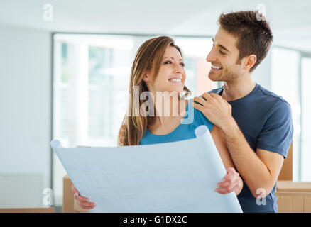 Young happy couple holding a project and planning their new house, relocation and renovation concept Stock Photo