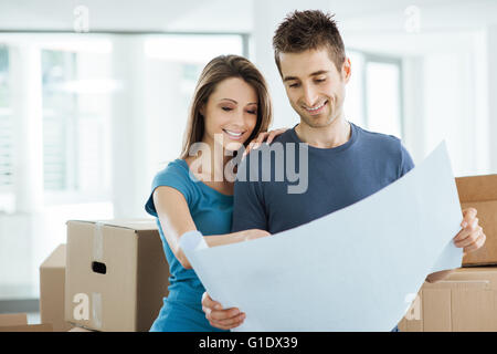 Young happy couple holding a project and planning their new house, relocation and renovation concept Stock Photo