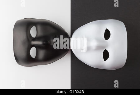 Black and white masks touching chins on contrasting backgrounds, Personality change theatrical concept Stock Photo