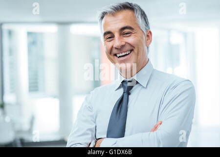 Successful businessman posing with crossed arms and smiling at camera Stock Photo