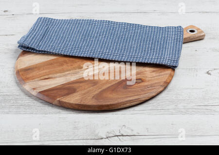 Blue napkin on round chopping board on white rustic wooden table. Horizontal image with copy space Stock Photo