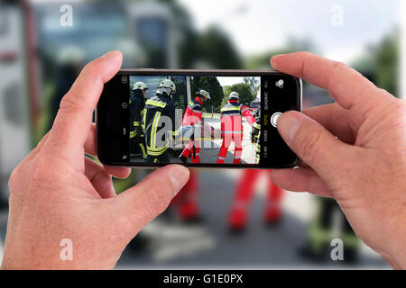 Onlookers take picture with a mobile phone camera, of an accident, symbolic image, photomontage, photo composition,