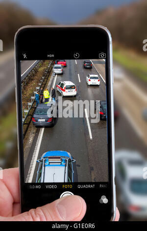 Onlookers take picture with a mobile phone camera, of an accident, symbolic image, photomontage, photo composition,