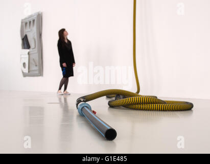 Hamburg, Germany. 13th May, 2016. A woman looks at an art work made of an extraction hose at an exhibition by artist Andreas Slominski at the Deichtorhallen exhibition hall in Hamburg, Germany, 13 May 2016. Slominksi created an art installation made of more than hundred portable toilets. Photo: Daniel Bockwoldt/dpa/Alamy Live News