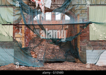 Old living house is under reconstruction, facade with arch is covered with green protection mesh Stock Photo