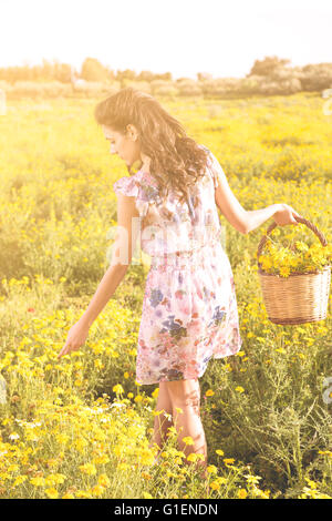 Pretty young woman in a daisy field at sunset. walking away Stock Photo