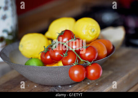 Cherry tomatoes on the vine in a fruit bowl with lemons Stock Photo