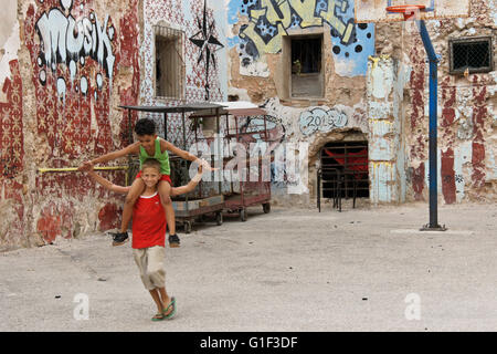 Boys playing in front of walls covered with graffiti, Havana, Cuba Stock Photo