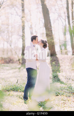 Happy bride and groom kissing in spring park holding hands Stock Photo