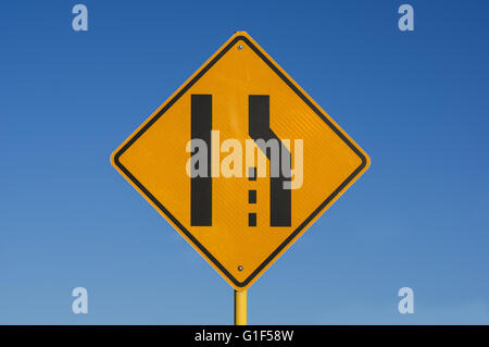 yellow and black right lane ends sign with blue sky background Stock Photo