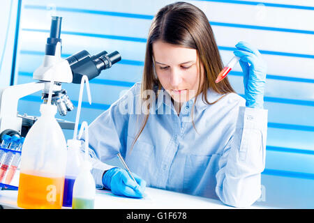 MODEL RELEASED. Female lab technician making notes in the laboratory. Stock Photo