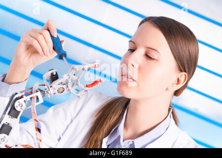 MODEL RELEASED. Female electrical engineer working on robotic arm. Stock Photo