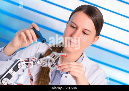 MODEL RELEASED. Female electrical engineer working on robotic arm. Stock Photo