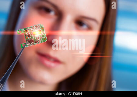 MODEL RELEASED. Female electrical engineer holding micro chip in tweezers. Stock Photo