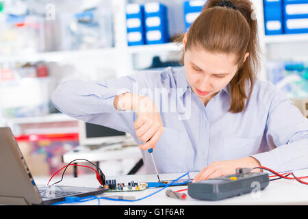 MODEL RELEASED. Female electrical engineer testing a circuit board. Stock Photo