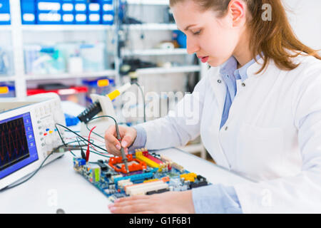 MODEL RELEASED. Female electrical engineer working on a circuit board. Stock Photo