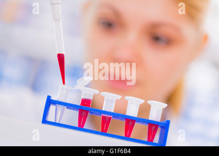 MODEL RELEASED. Female scientist using a pipette with test tubes. Stock Photo