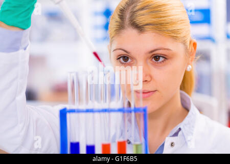 MODEL RELEASED. Female scientist using a pipette with test tubes. Stock Photo