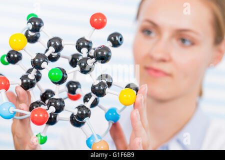 MODEL RELEASED. Female chemist examining molecular model. Stock Photo