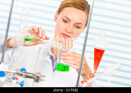 MODEL RELEASED. Female chemist pouring chemicals into glassware in laboratory. Stock Photo