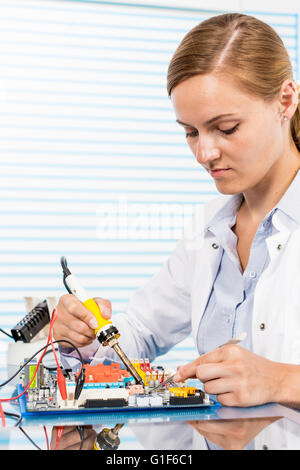 MODEL RELEASED. Female technician working on a circuit board. Stock Photo