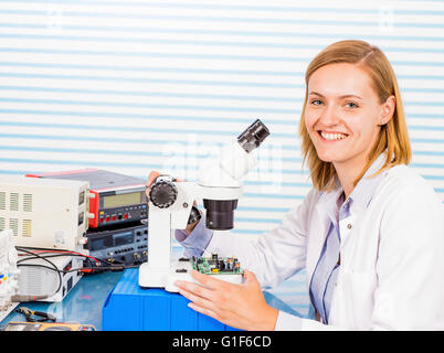 MODEL RELEASED. Female technician with microscope in the laboratory, portrait. Stock Photo
