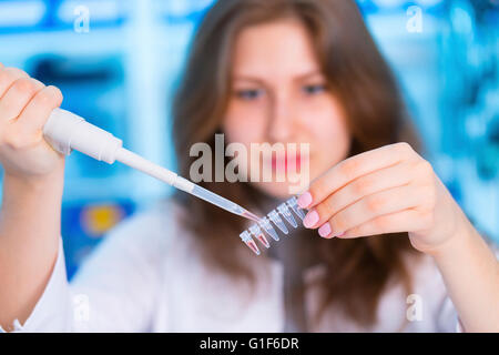 MODEL RELEASED. Female scientist using pipette, holding micro tubes. Stock Photo