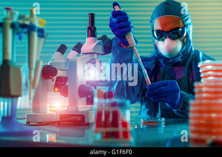 MODEL RELEASED. Person wearing protective clothing working in a microbiology laboratory. Stock Photo