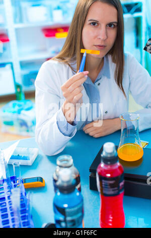 MODEL RELEASED. Female scientist testing food samples in a flask. Stock Photo