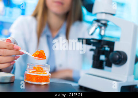 MODEL RELEASED. Female scientist testing caviar in a laboratory. Stock Photo