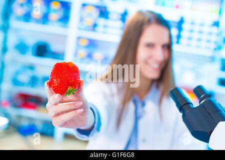 MODEL RELEASED. Female scientist holding strawberry in a laboratory. Stock Photo