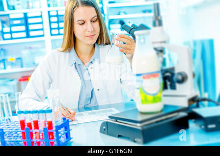 MODEL RELEASED. Female scientist holding a glass beaker with milk. Stock Photo