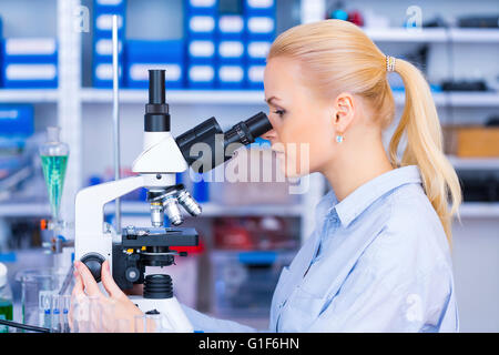 MODEL RELEASED. Female scientist using microscope in the laboratory. Stock Photo