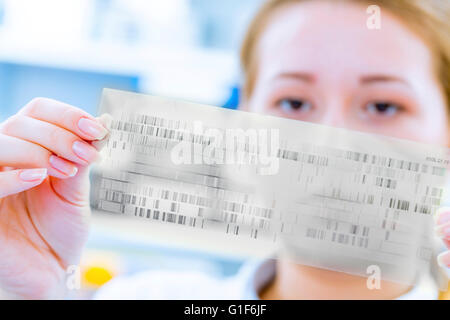 MODEL RELEASED. Female scientist holding dna sequencing results. Stock Photo