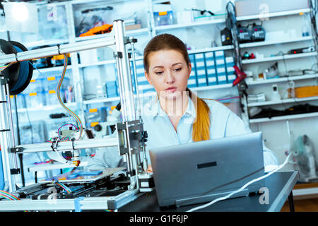 MODEL RELEASED. Young woman using a 3d printer. Stock Photo