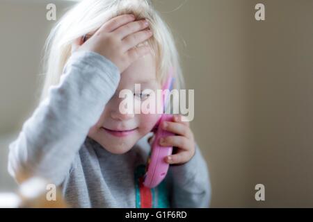 MODEL RELEASED. Toddler playing with toy telephone, portrait. Stock Photo