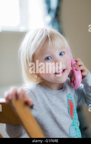 MODEL RELEASED. Toddler playing with toy telephone, portrait. Stock Photo