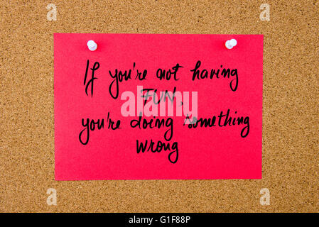 Red paper note with handwritten text If You Are Not Having Fun, You Are Doing Something Wrong pinned on cork board with white thumbtacks Stock Photo