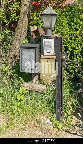 sunny illuminated scenery showing a garden gate with letter boxes, doorbell and lamp Stock Photo