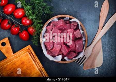 Raw meat  cut into smaller pieces, fresh raw chopped beef in wooden bowl, top view Stock Photo