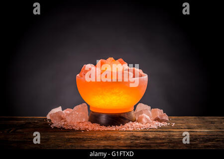 Turned on Himalayan pink salt lamp on a wooden table Stock Photo